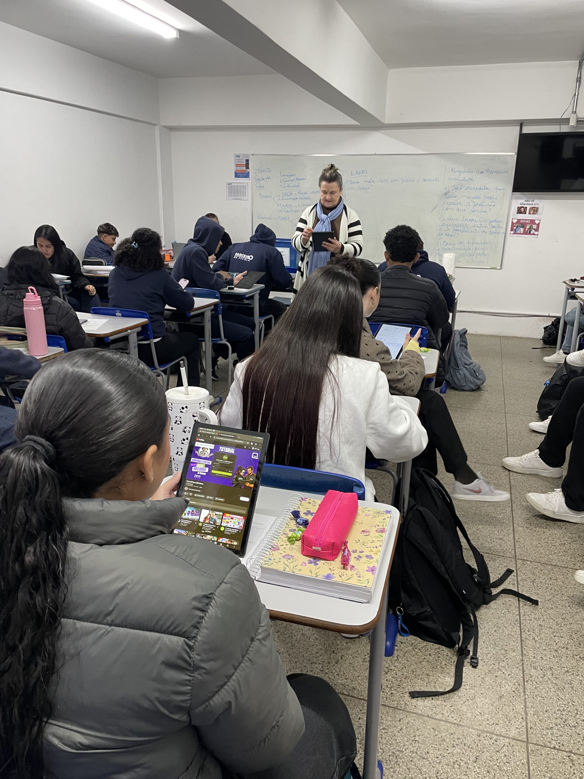 Professora conduzindo aula com estudantes usando tablets
